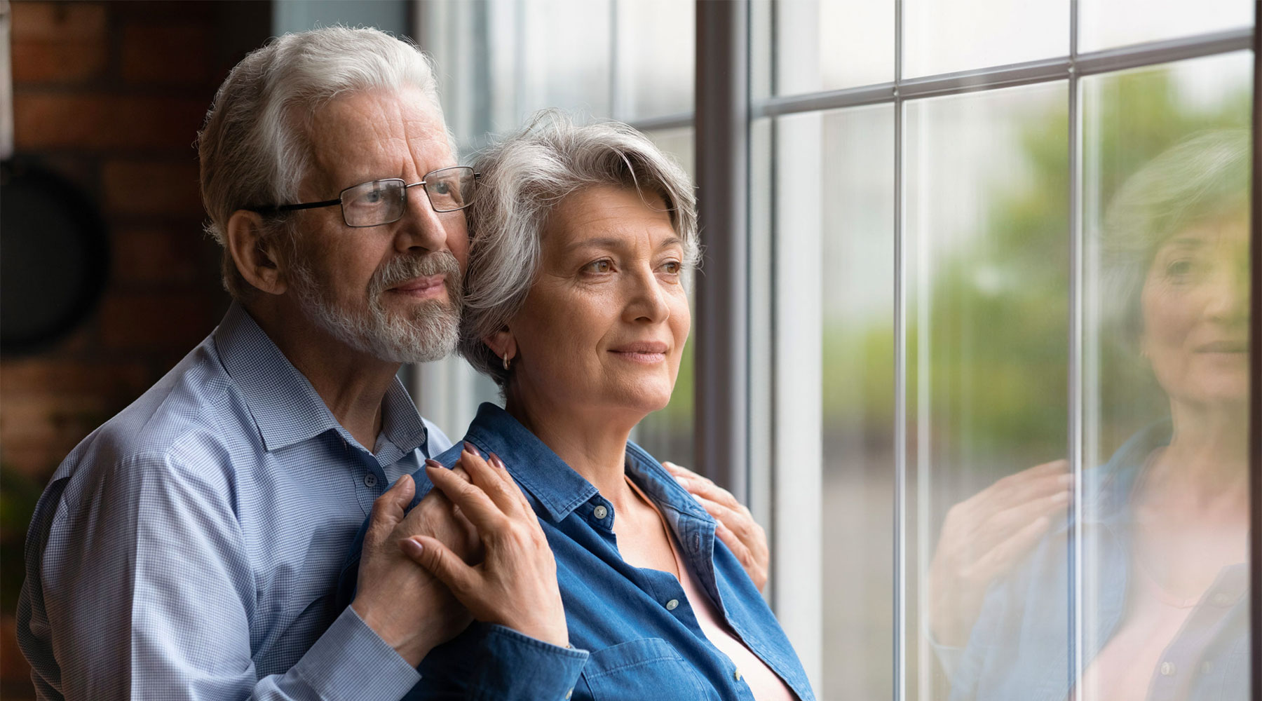 Older Couple Holding looking out of a window